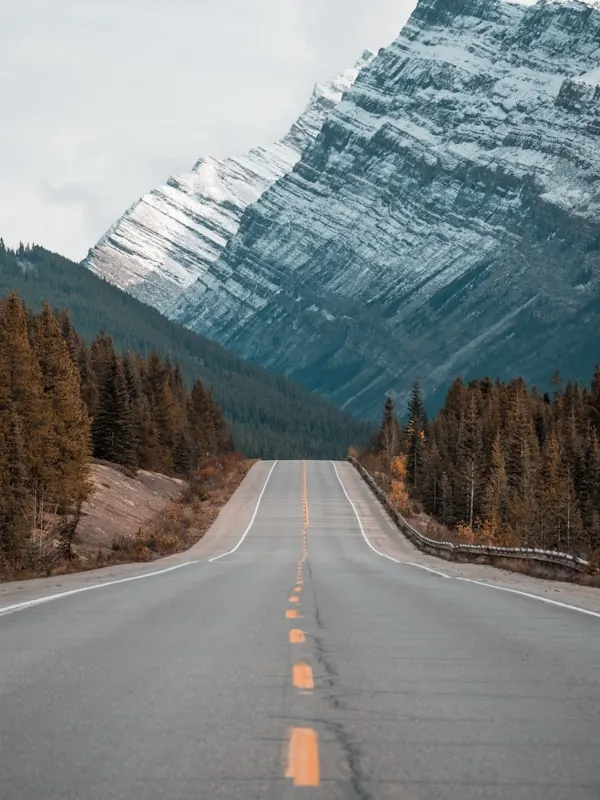 An open highway leading toward snow-capped mountains